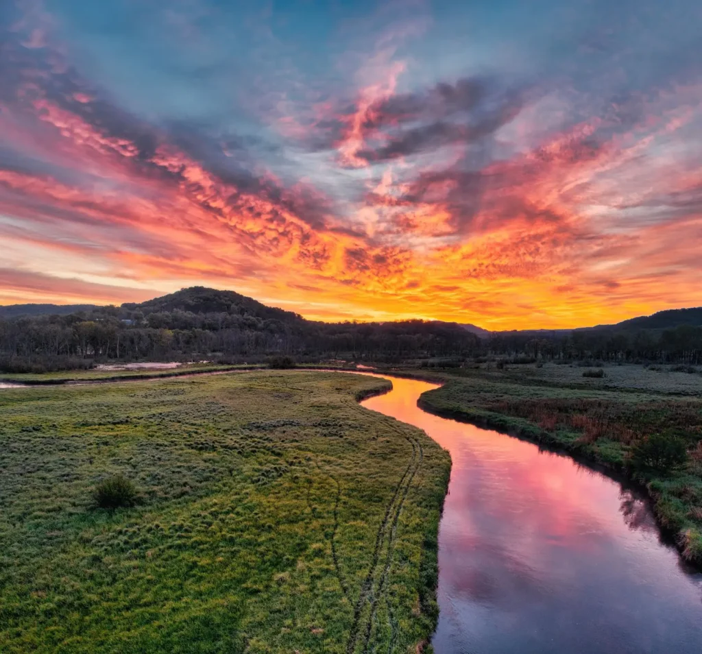 A river winding through a valley meadow at dusk